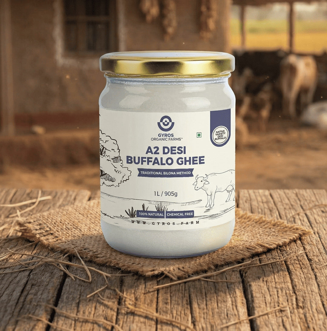 Gyros Organic Farms A2 desi buffalo ghee 1L jar placed on a wooden surface with a warm rural farm backdrop.