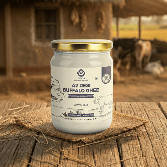 Gyros Organic Farms A2 desi buffalo ghee 500ml jar placed on a wooden surface with a warm rural farm backdrop.
