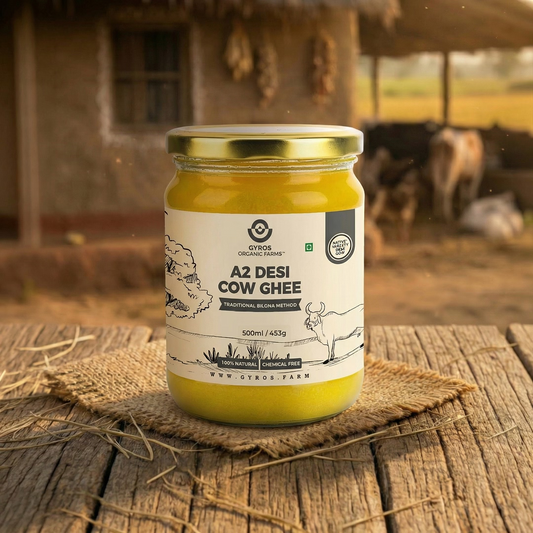 Gyros A2 desi cow ghee 500ml glass jar placed on a rustic wooden surface with a farm background.