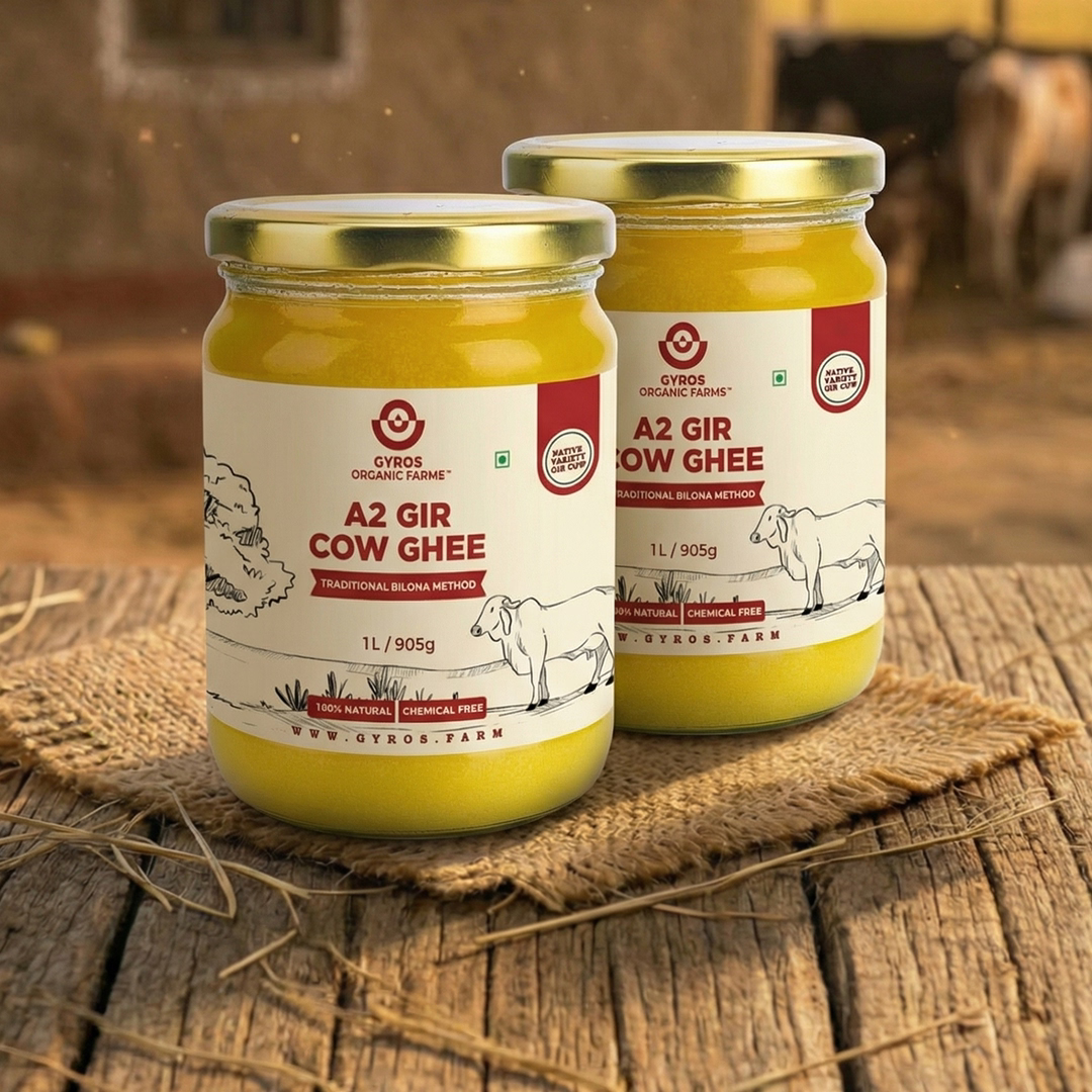 Two jars of Gyros Organic Farms A2 Gir Cow Ghee on a wooden surface with a blurred background.