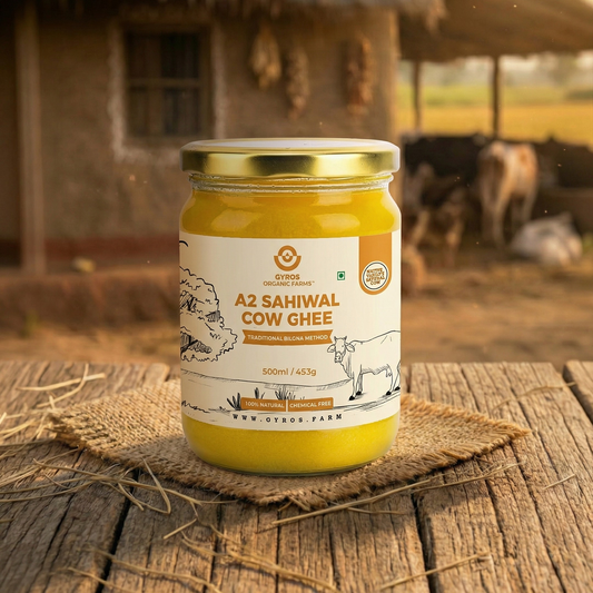 Gyros A2 Sahiwal cow ghee 500ml glass jar placed on a rustic wooden surface with a farm background.