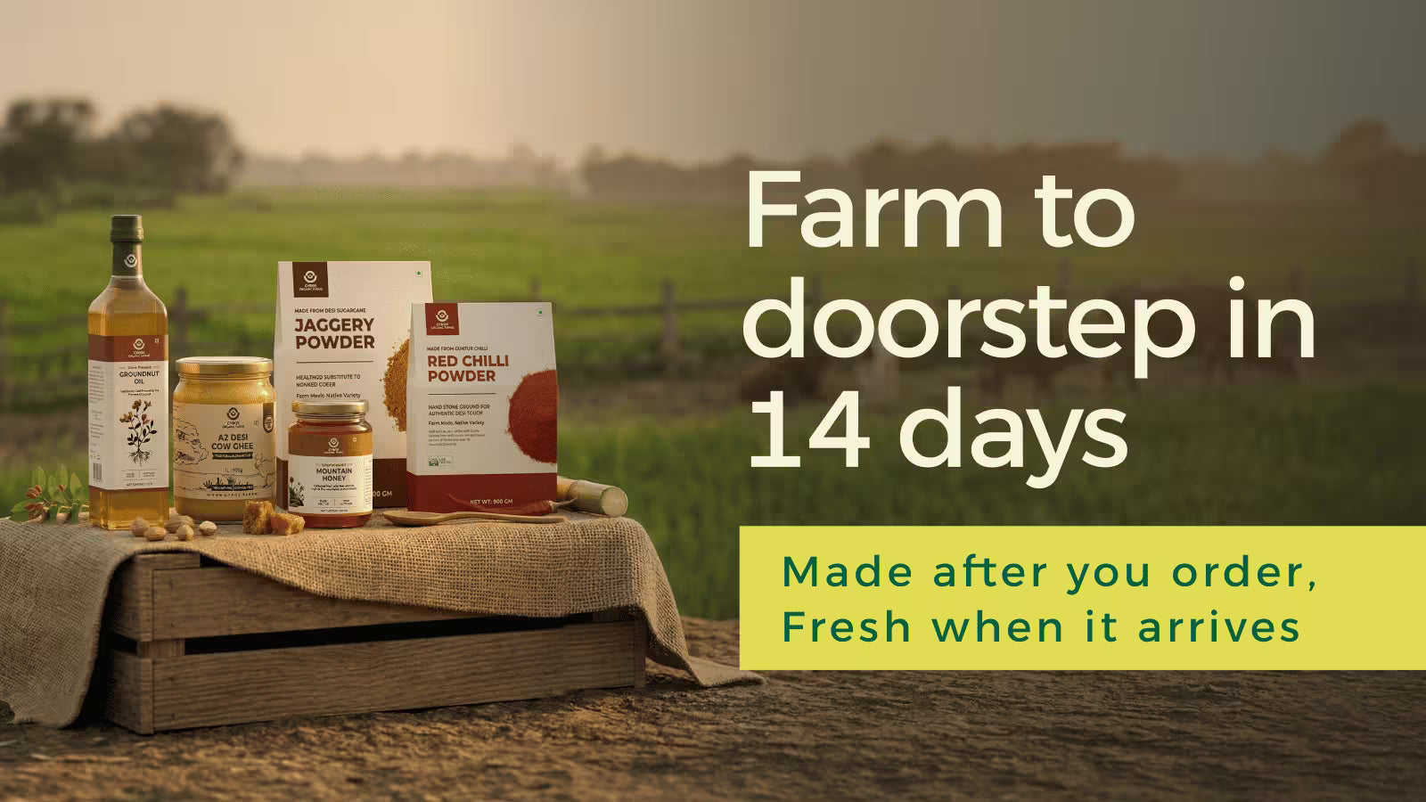 Gyros Organic Farms products including A2 cow ghee, jaggery powder, red chilli powder and groundnut oil displayed on a wooden crate in a farm field with message “Farm to doorstep in 14 days”